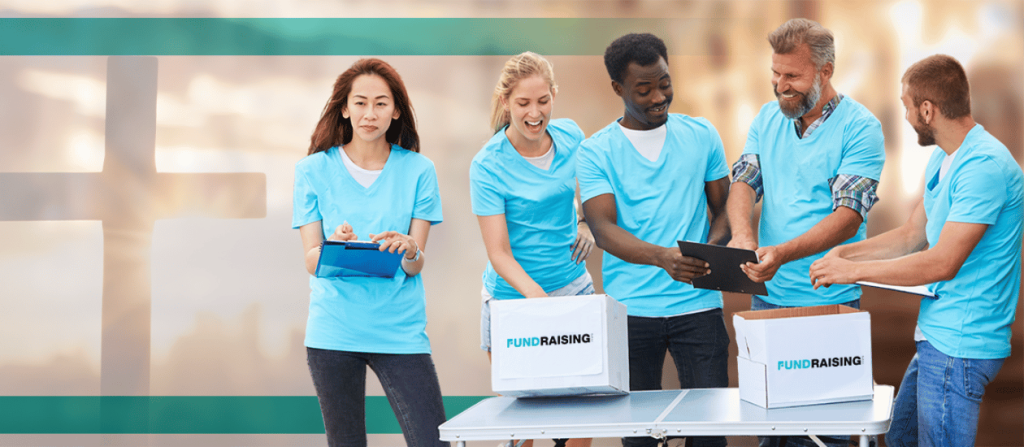 A diverse group of volunteers in light blue shirts organizing a fundraising event, with boxes labeled 'Fundraising' on a table and a blurred cross in the background.