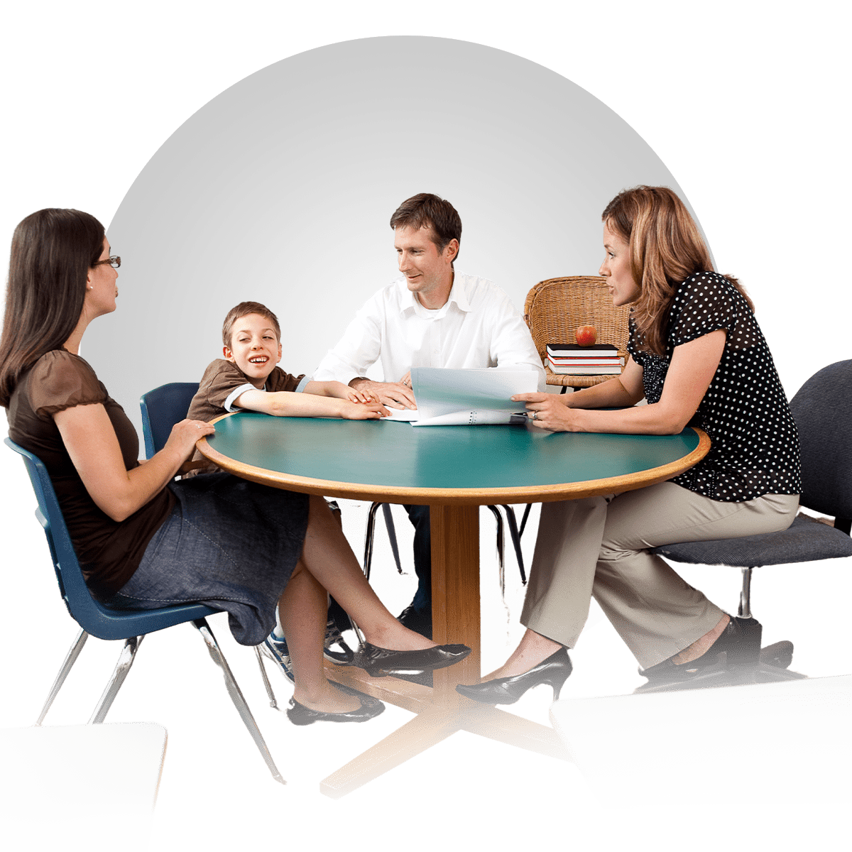 A group of four people sitting around a round table having a discussion, including two adults, a child smiling enthusiastically, and another adult holding papers.