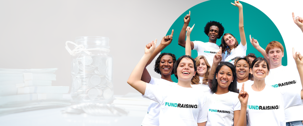 Group of diverse volunteers raising their hands and smiling, wearing white fundraising t-shirts with a jar of coins in the background.