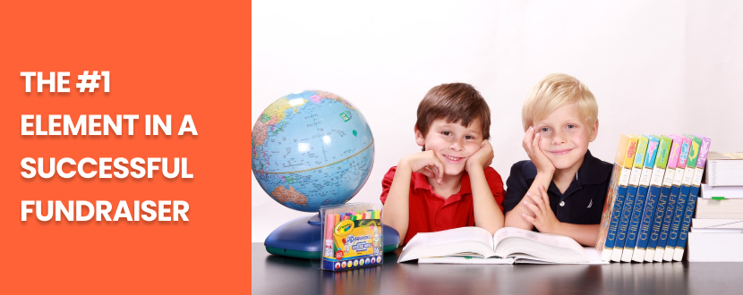 Two young boys smiling while seated at a desk with school supplies, including a globe, books, and crayons, next to the text 'The #1 Element in a Successful Fundraiser' on an orange background.