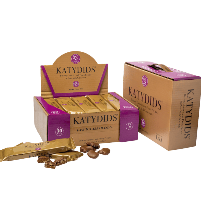 Katydids candy packaging displayed with caramel and pecan clusters coated in milk chocolate.